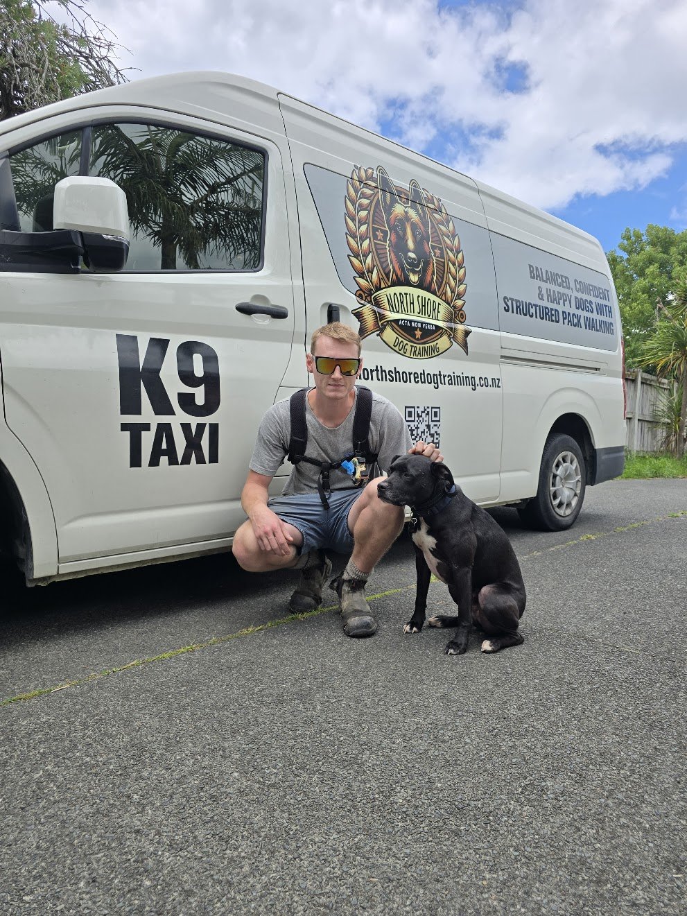 Taine with a young dog beside the K9 Taxi van